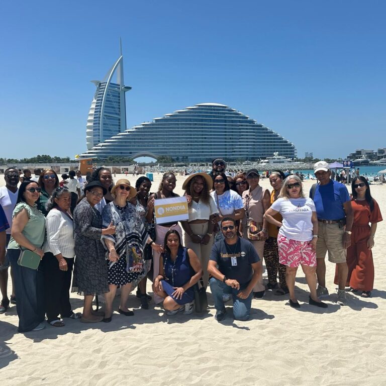 Grupo de viajeros en la playa con el Burj Al Arab de fondo en Dubái
